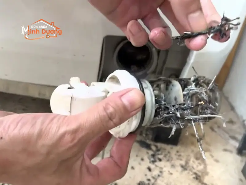 Thợ kỹ thuật tháo kiểm tra bầu bơm xả máy giặt bị hở gioăng