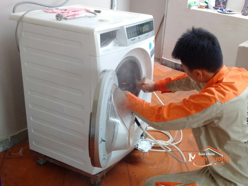 Thợ sửa máy giặt Sơn Tây đang dùng máy bơm áp lực cao xịt rửa cặn bẩn lồng giặt.